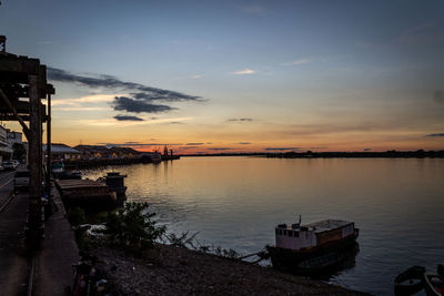 Boat moored in lake against sky during sunset