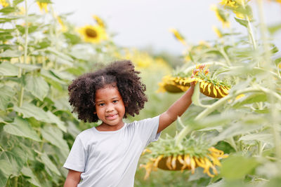 Portrait of smiling girl with flowers against plants