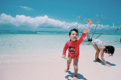 Full length of siblings at beach against sky