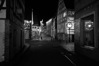 Illuminated street amidst buildings in city at night