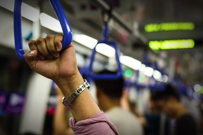 Cropped hand of woman holding handle in bus