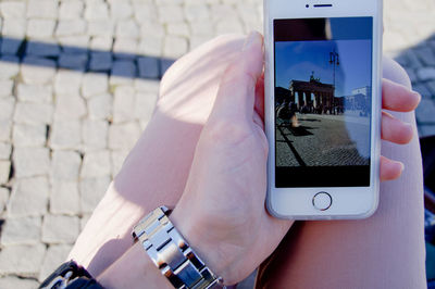 Midsection of woman holding smart phone with brandenburg gate photograph