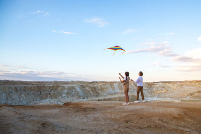 Rear view of woman standing at beach against sky
