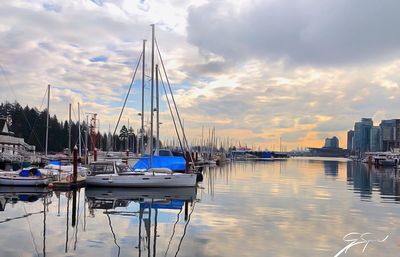Boats moored at harbor against sky during sunset