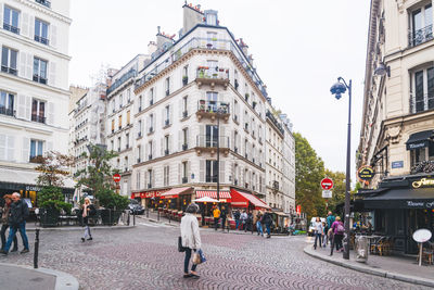 People walking on street against buildings in city