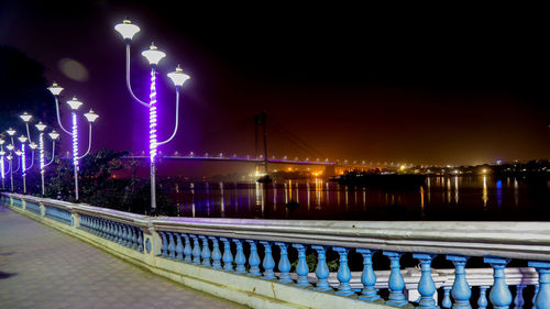 Illuminated bridge over river in city at night