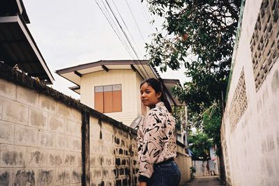 Portrait of woman standing against building