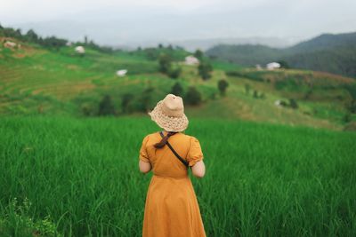 Rear view of woman wearing hat on field