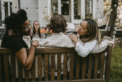 Female talking to young friend behind partner during social gathering