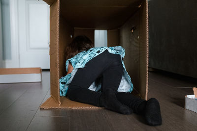 Toddler girl playing in large cardboard box