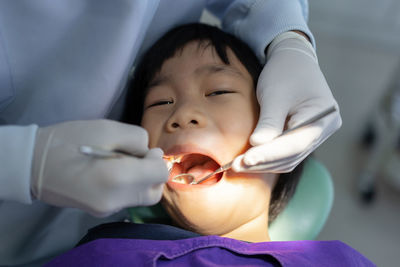 Hand of doctor dentist is working on the teeth of dentist using ultraviolet light on the boy's teeth