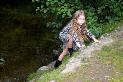 Beautiful young woman in front of stream amidst plants