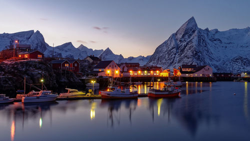 Boats on lake by snowcapped mountains during sunset