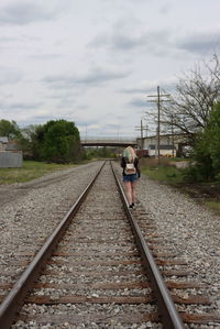 Rear view of man walking on railroad track