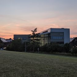 Buildings on field against sky during sunset