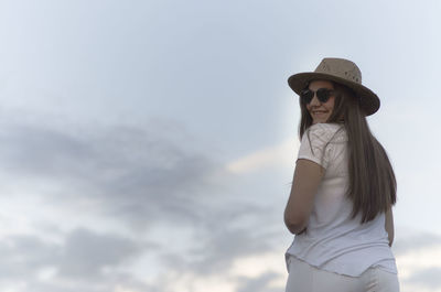 Portrait of a beautiful girl in white clothes and hat posing playfully in rural background