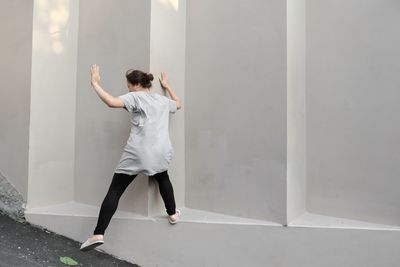 Rear view of woman standing against white wall