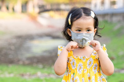 Cute girl standing outdoor wearing medical face mask to prevent flu, pollution and covid 19.