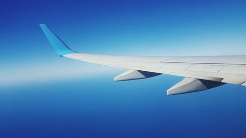 Cropped of airplane wing against clear blue sky