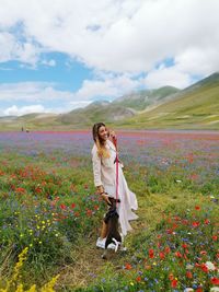 Side view of young woman with dog on field against sky