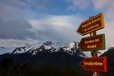 Information signs by snowcapped mountains against sky