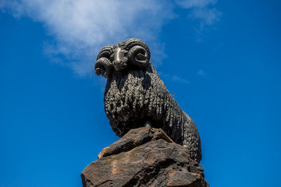 Low angle view of bird statue against blue sky