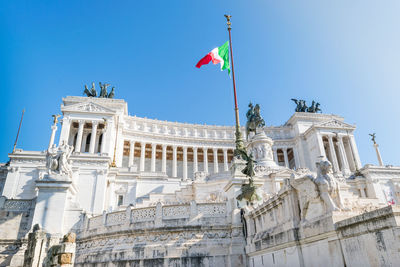 Low angle view of flags against clear blue sky