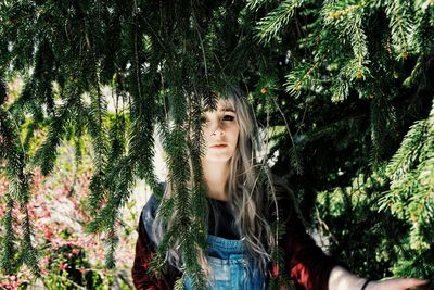 Portrait of beautiful woman standing by trees