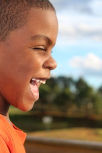 Close-up of boy smiling against sky