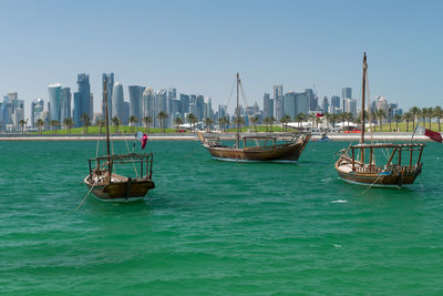 Sailboats moored on sea against buildings in city