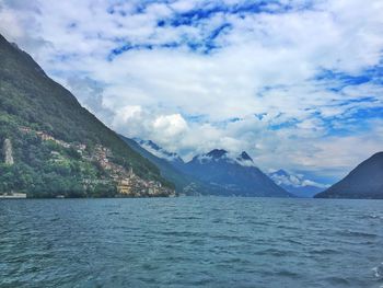 Scenic view of sea by mountains against sky