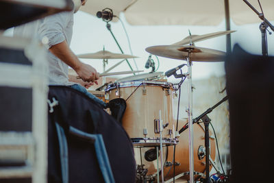 Midsection of man playing drum set