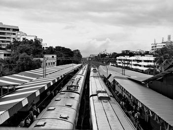 Trains at railroad station in city against sky