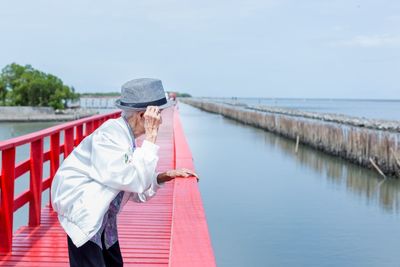 Senior man standing on pier over sea against sky