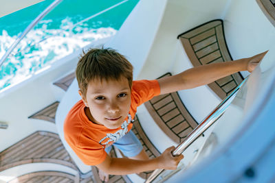 Boy sailing on yacht going down the stairs from deck
