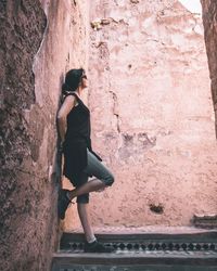 Side view of woman standing against wall