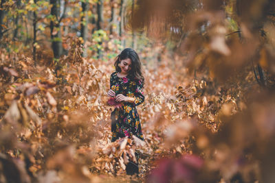 Portrait of young woman standing on field during autumn