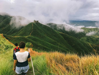 Rear view of man looking at mountains against sky