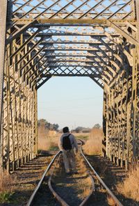 Rear view of man walking on railway tracks