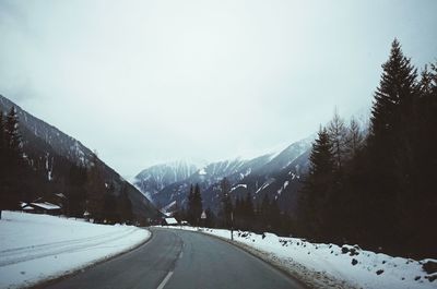 Road amidst snowcapped mountains against sky