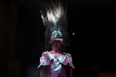Girl with powder paint tossing hair while standing outdoors