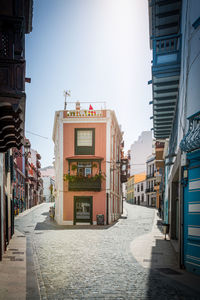 Empty alley amidst buildings in city against sky