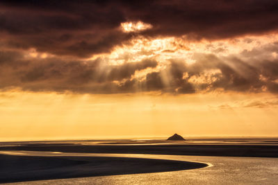 Scenic view of sea against dramatic sky during sunset