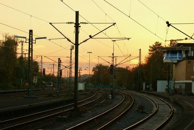 Railroad tracks in city against sky during sunset