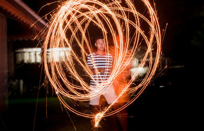 Blurred motion of man making light painting at night