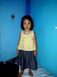 Portrait of girl standing against blue wall