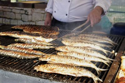 Midsection of man preparing fish on barbecue grill