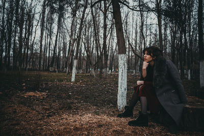 Side view of woman sitting in forest