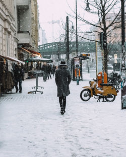 Man walking on snow covered road in city