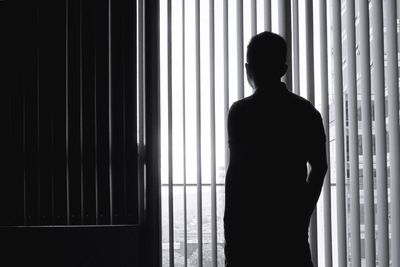 Rear view of man standing by window